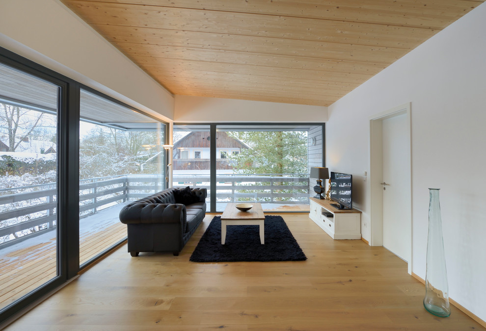 Inspiration för ett mellanstort minimalistiskt separat vardagsrum, med vita väggar, ljust trägolv och en fristående TV