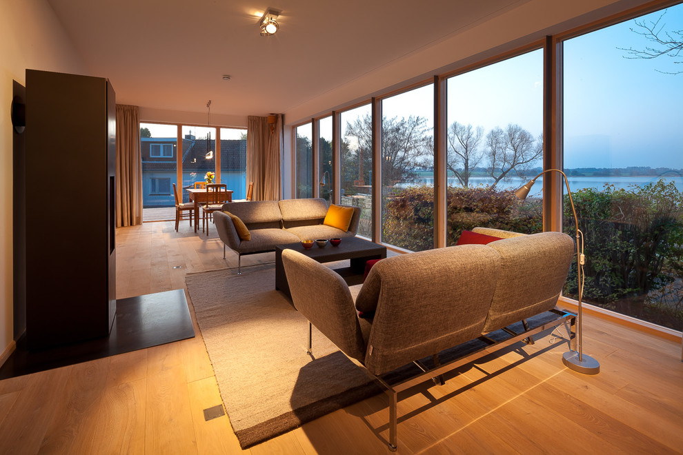 Großes, Repräsentatives, Offenes Modernes Wohnzimmer mit weißer Wandfarbe, braunem Holzboden und Kamin in Hamburg