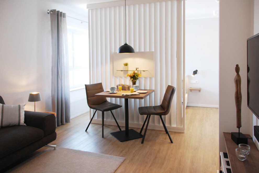 Immagine di un soggiorno scandinavo di medie dimensioni e aperto con pareti beige, pavimento in vinile, TV a parete e pavimento marrone