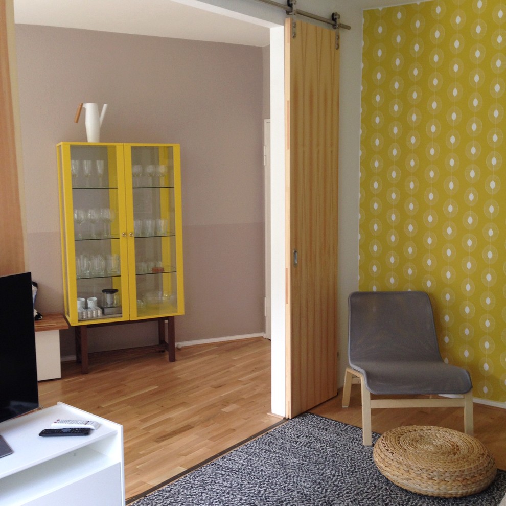 Exempel på ett litet nordiskt allrum med öppen planlösning, med en väggmonterad TV och flerfärgade väggar