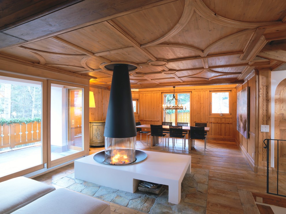 Стильный дизайн: большая открытая гостиная комната в стиле рустика с коричневыми стенами, деревянным полом, печью-буржуйкой и коричневым полом без телевизора - последний тренд