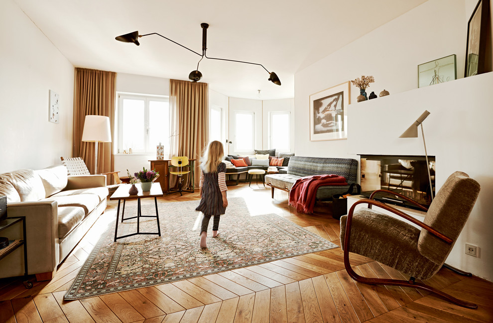 Exemple d'une très grande salle de séjour tendance fermée avec un mur blanc, un sol en bois brun, une cheminée d'angle, un manteau de cheminée en plâtre et aucun téléviseur.