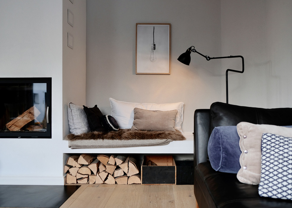 Mittelgroßes, Fernseherloses, Offenes Nordisches Wohnzimmer mit grauer Wandfarbe, hellem Holzboden, Kaminofen und verputzter Kaminumrandung in München