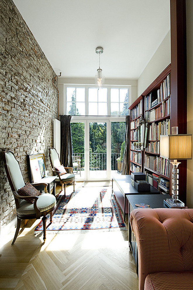 Imagen de sala de estar con biblioteca cerrada tradicional pequeña sin chimenea y televisor con suelo de madera clara y paredes beige