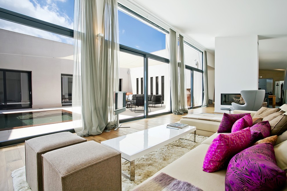 Inspiration for a large contemporary formal and open concept medium tone wood floor living room remodel in Stuttgart with a two-sided fireplace, white walls, a plaster fireplace and a tv stand