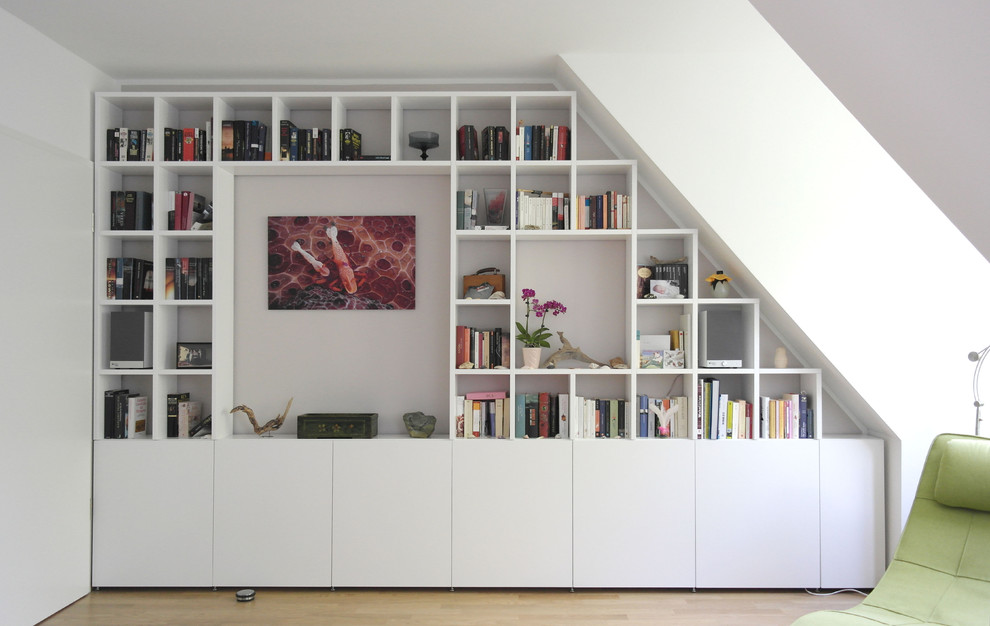 Immagine di un grande soggiorno contemporaneo aperto con libreria, pareti bianche, parquet chiaro, nessun camino e pavimento beige