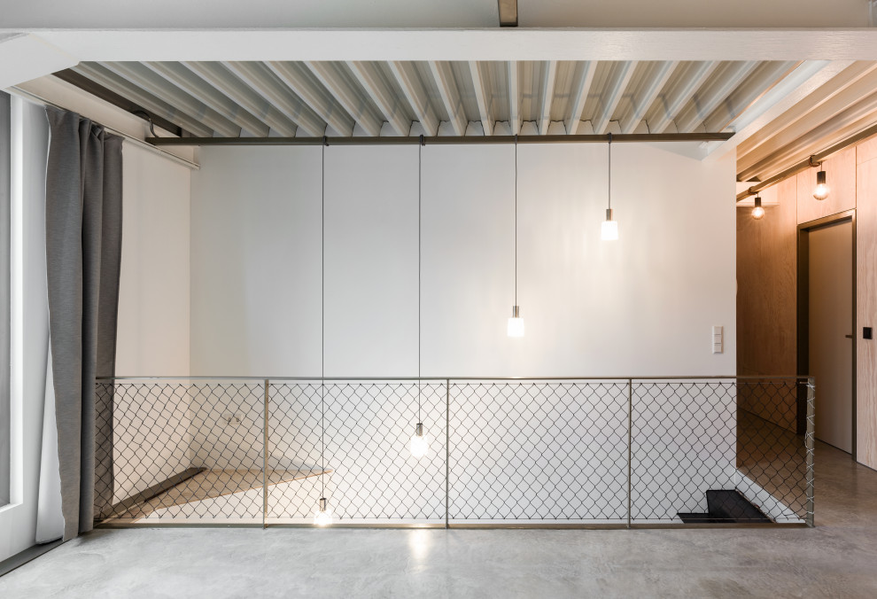 Idée de décoration pour un grand salon mansardé ou avec mezzanine urbain avec un mur blanc, sol en béton ciré et un sol gris.