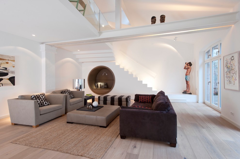 Источник вдохновения для домашнего уюта: большая открытая гостиная комната в современном стиле с белыми стенами, светлым паркетным полом и коричневым диваном без камина, телевизора