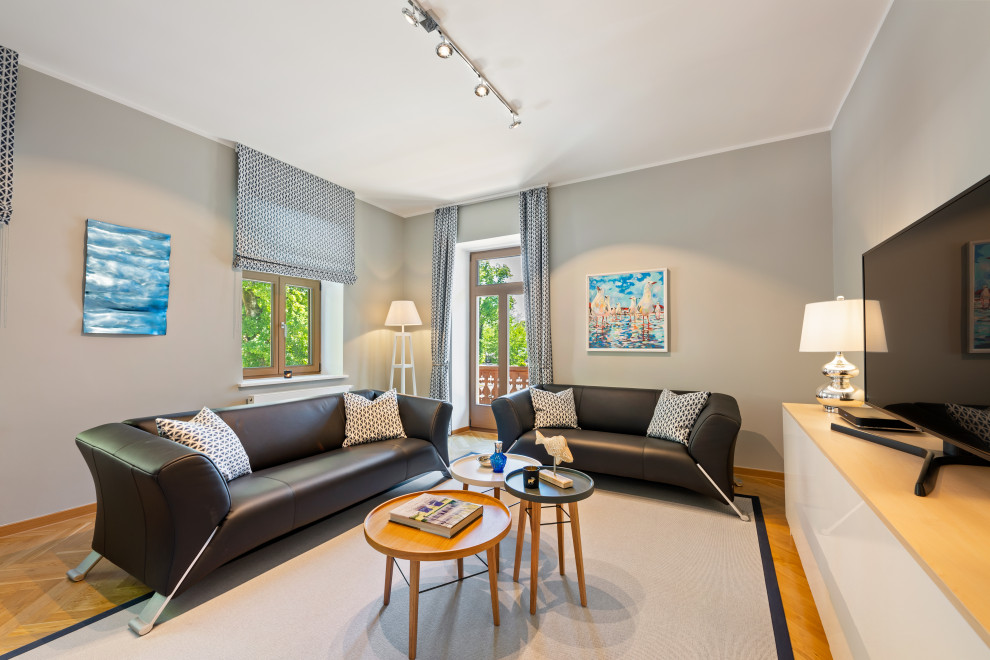 Mittelgroßes, Abgetrenntes Stilmix Wohnzimmer mit grauer Wandfarbe, hellem Holzboden, freistehendem TV und gelbem Boden in Sonstige