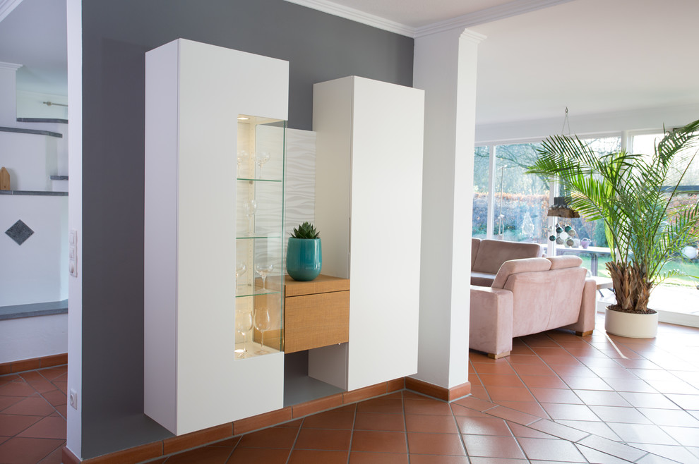 Mittelgroßes Modernes Wohnzimmer mit grauer Wandfarbe, Terrakottaboden und freistehendem TV in Sonstige