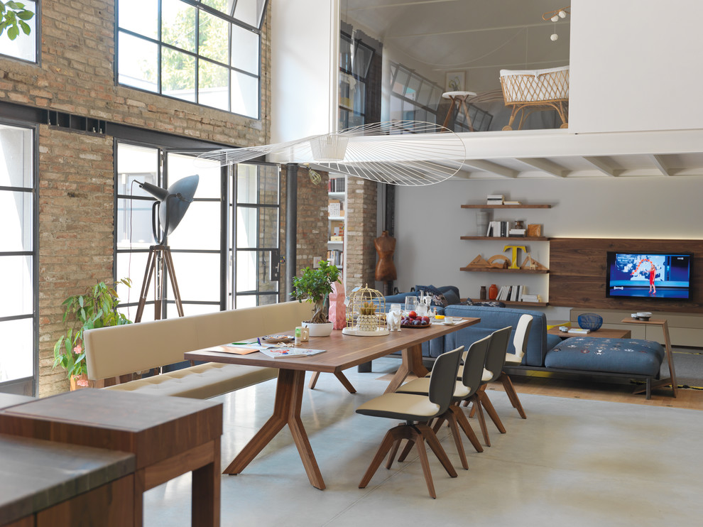 Immagine di un ampio soggiorno industriale stile loft con sala formale, pareti bianche, pavimento in cemento, nessun camino, pavimento grigio e TV a parete