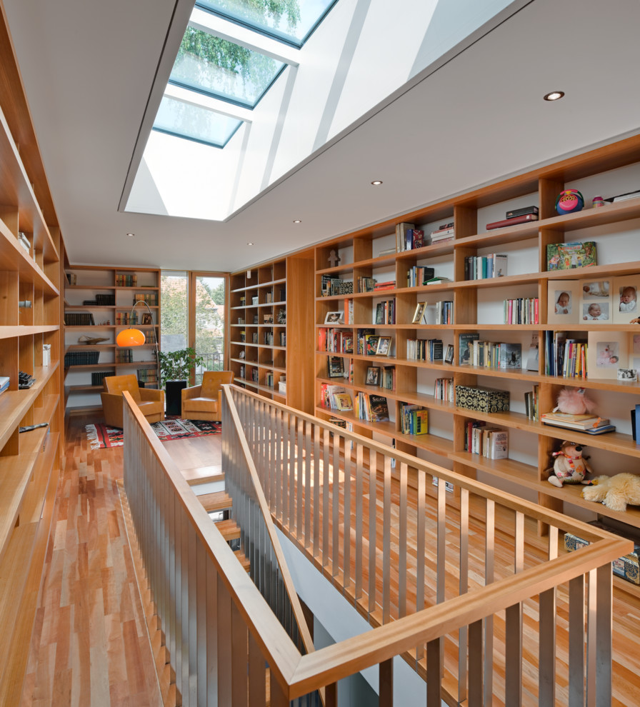 Idéer för ett stort modernt allrum på loftet, med ett bibliotek, vita väggar och mellanmörkt trägolv