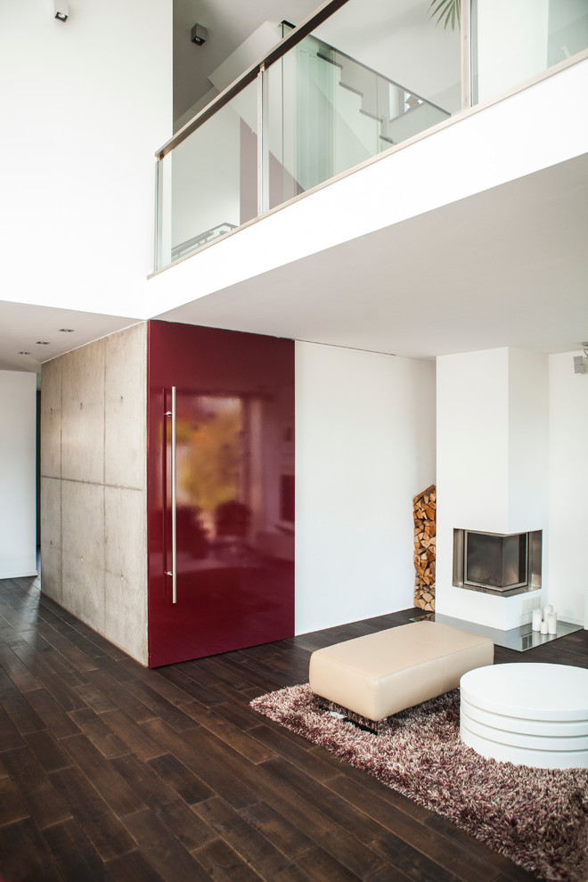Immagine di un ampio soggiorno minimalista con pareti bianche, pavimento in legno verniciato, camino ad angolo, cornice del camino in intonaco e pavimento marrone