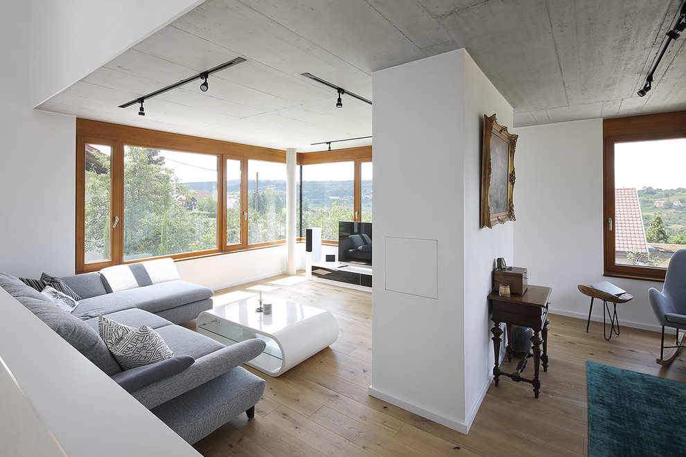 Mittelgroßes Modernes Wohnzimmer im Loft-Stil mit weißer Wandfarbe, braunem Holzboden, freistehendem TV und braunem Boden