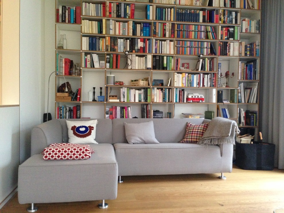 Inspiration för moderna vardagsrum, med ett bibliotek, vita väggar och mellanmörkt trägolv