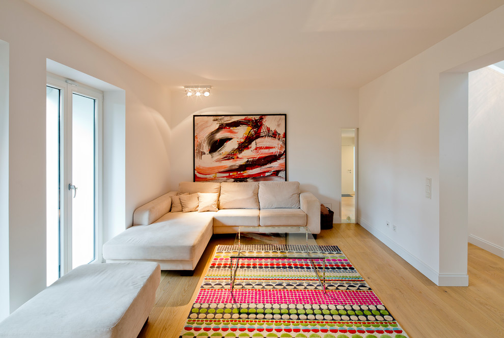 Ejemplo de sala de estar cerrada actual de tamaño medio sin chimenea y televisor con paredes blancas y suelo de madera en tonos medios