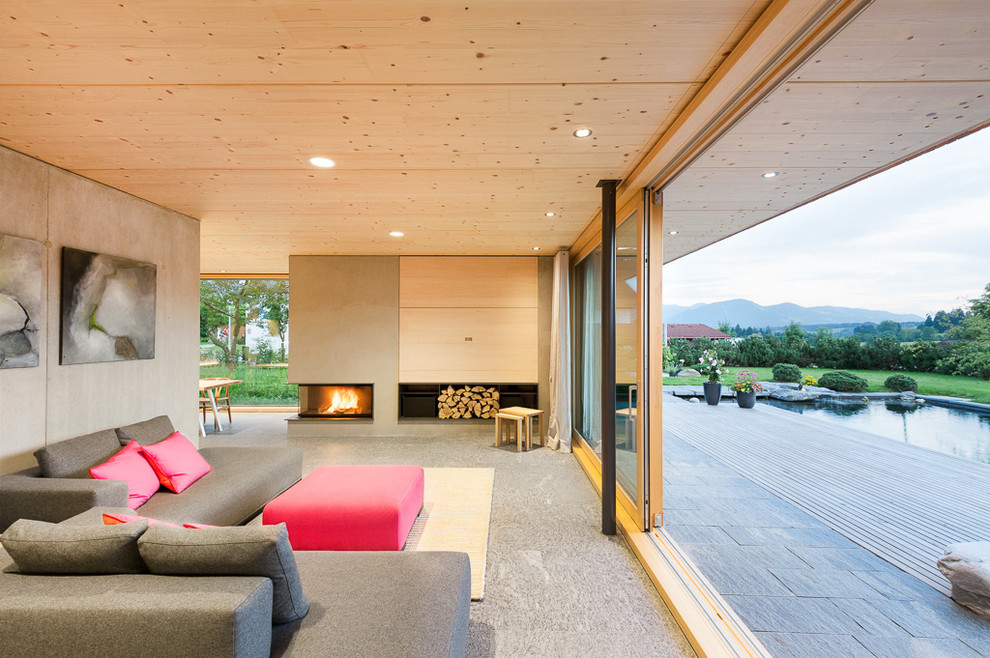 Пример оригинального дизайна: огромная открытая гостиная комната в скандинавском стиле с угловым камином, фасадом камина из бетона и серыми стенами без телевизора