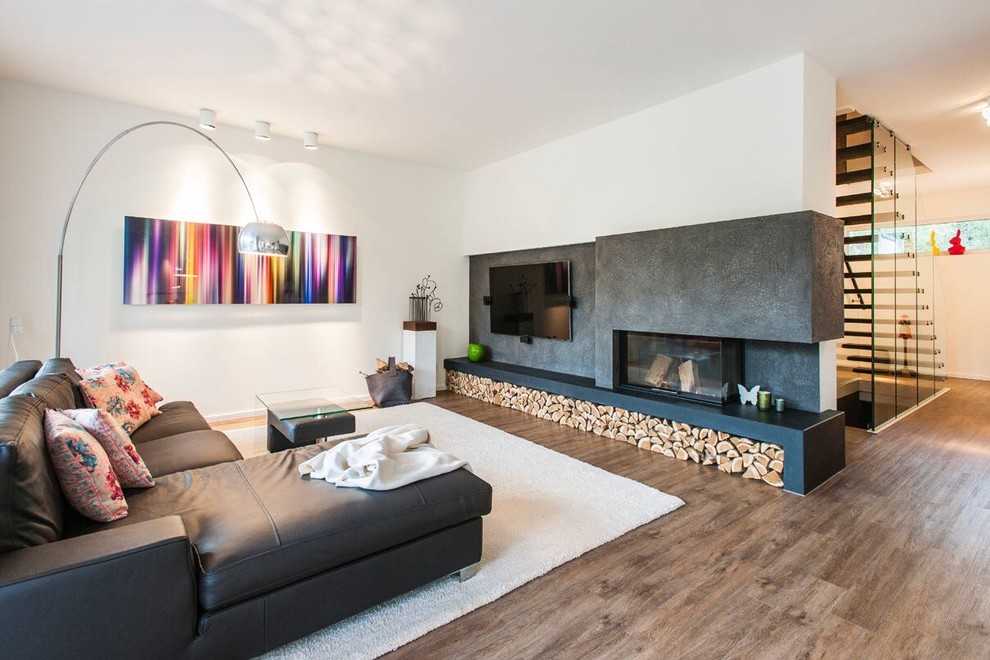 Идея дизайна: открытая гостиная комната среднего размера в современном стиле с белыми стенами, паркетным полом среднего тона, двусторонним камином, телевизором на стене и коричневым полом