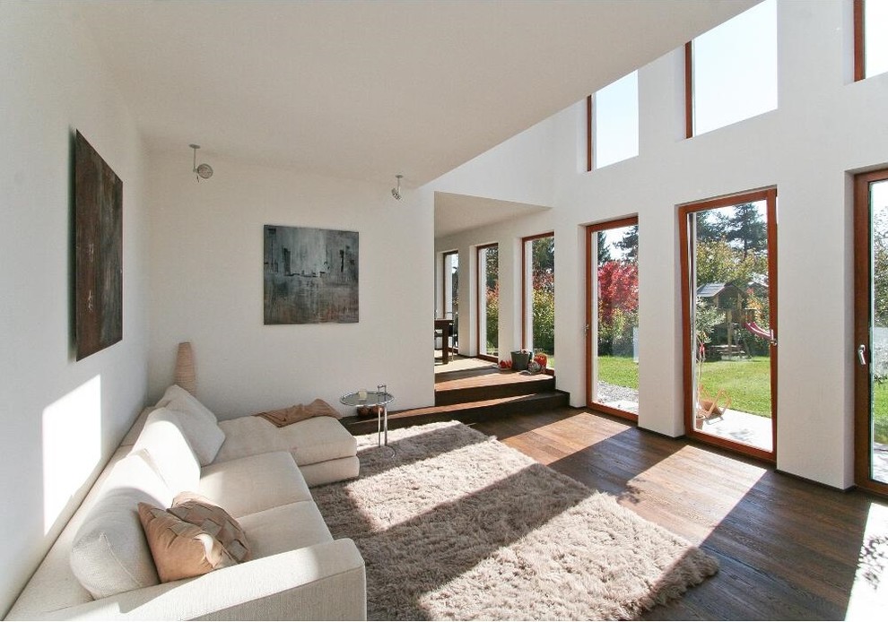 Geräumiges, Offenes, Fernseherloses Modernes Wohnzimmer ohne Kamin mit weißer Wandfarbe und dunklem Holzboden in München