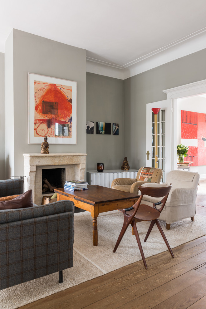 This is an example of a medium sized classic enclosed living room in Hamburg with grey walls, painted wood flooring, a standard fireplace, a stone fireplace surround, a built-in media unit and brown floors.