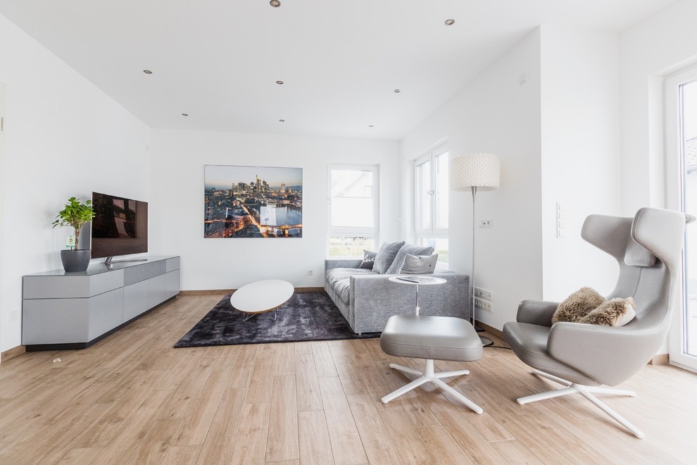 Kleines, Offenes Modernes Wohnzimmer mit weißer Wandfarbe, braunem Holzboden, freistehendem TV und braunem Boden in Frankfurt am Main