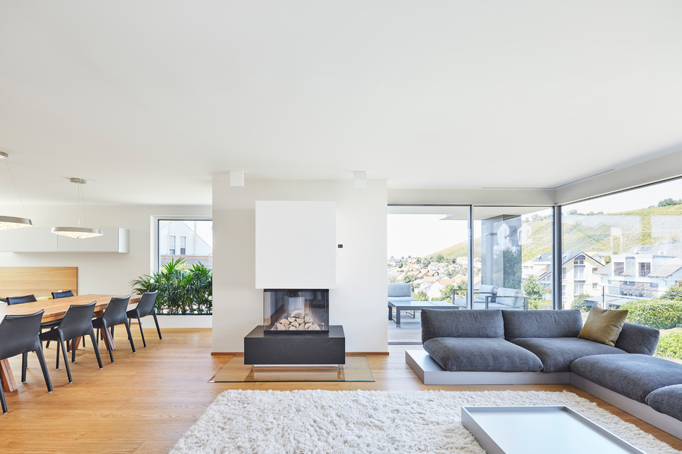 Mittelgroßes, Offenes Modernes Wohnzimmer mit weißer Wandfarbe, braunem Holzboden, Kamin, verputzter Kaminumrandung und braunem Boden in Stuttgart