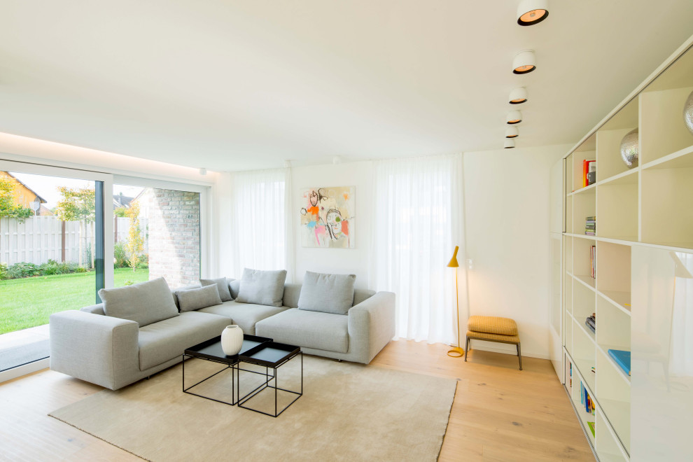 Inspiration pour une salle de séjour design de taille moyenne et ouverte avec un mur blanc, parquet clair, une cheminée double-face, un manteau de cheminée en plâtre, un téléviseur indépendant et un sol beige.