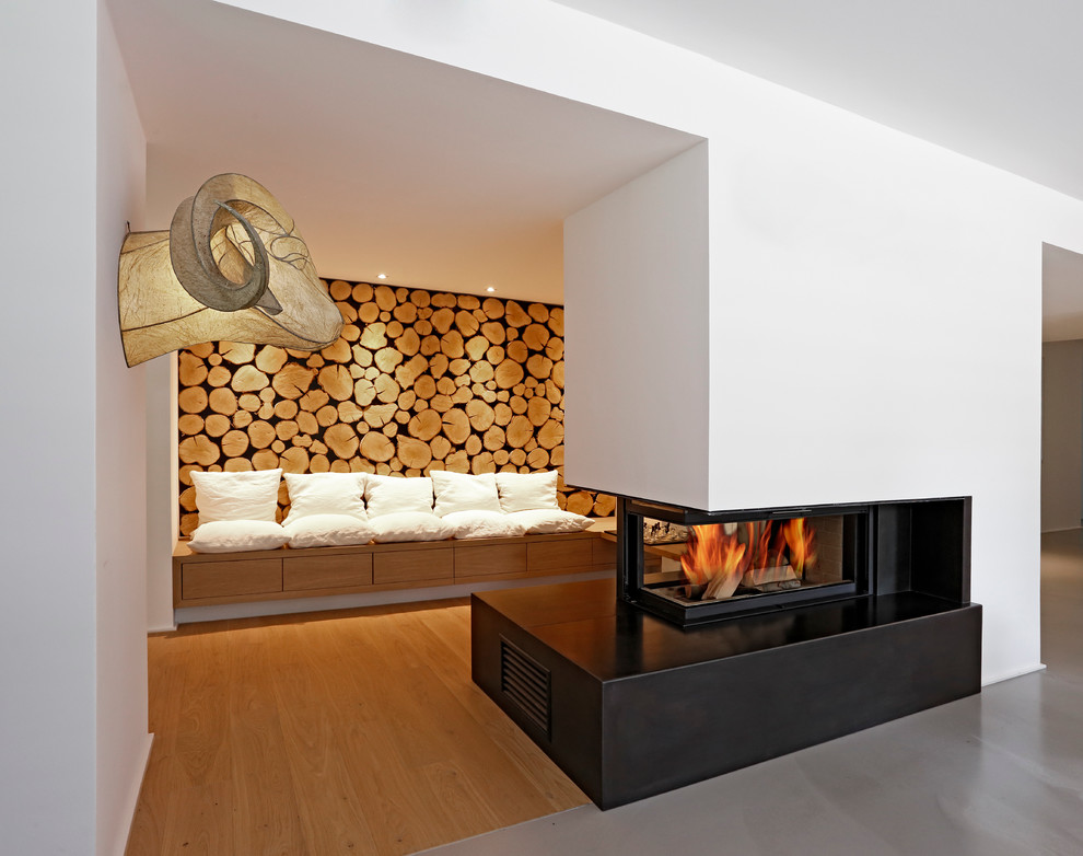 Foto de salón para visitas abierto minimalista pequeño con suelo de madera clara, chimenea de doble cara y paredes blancas