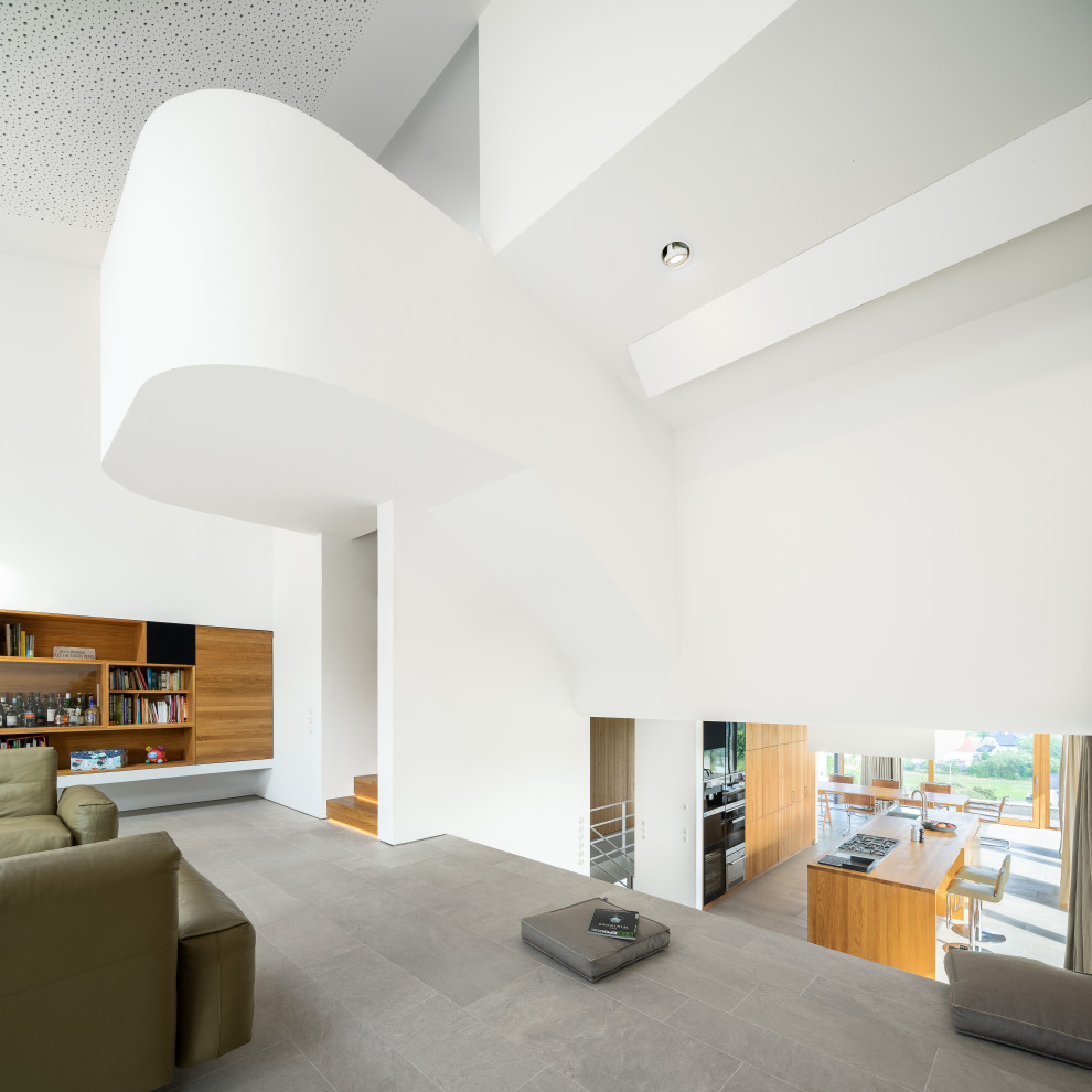 Geräumiges, Repräsentatives, Offenes Modernes Wohnzimmer mit weißer Wandfarbe, Porzellan-Bodenfliesen und grauem Boden in Sonstige