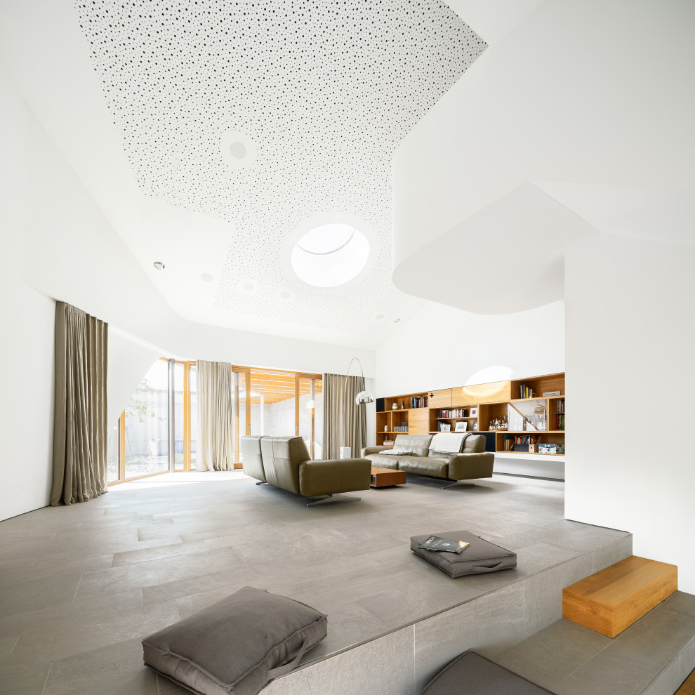 Источник вдохновения для домашнего уюта: огромная парадная, открытая гостиная комната в современном стиле с белыми стенами, полом из керамогранита и серым полом