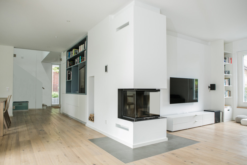 Offene Moderne Bibliothek mit weißer Wandfarbe, hellem Holzboden, Eckkamin, TV-Wand und Kaminumrandung aus Metall in Düsseldorf