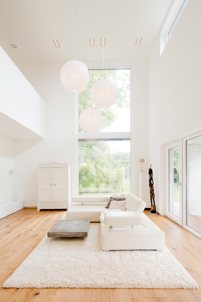 Repräsentatives, Offenes Nordisches Wohnzimmer ohne Kamin mit weißer Wandfarbe und hellem Holzboden in Köln
