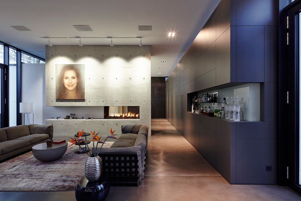 На фото: большая открытая гостиная комната в современном стиле с домашним баром, белыми стенами, полом из винила, двусторонним камином, фасадом камина из бетона и серым полом без телевизора