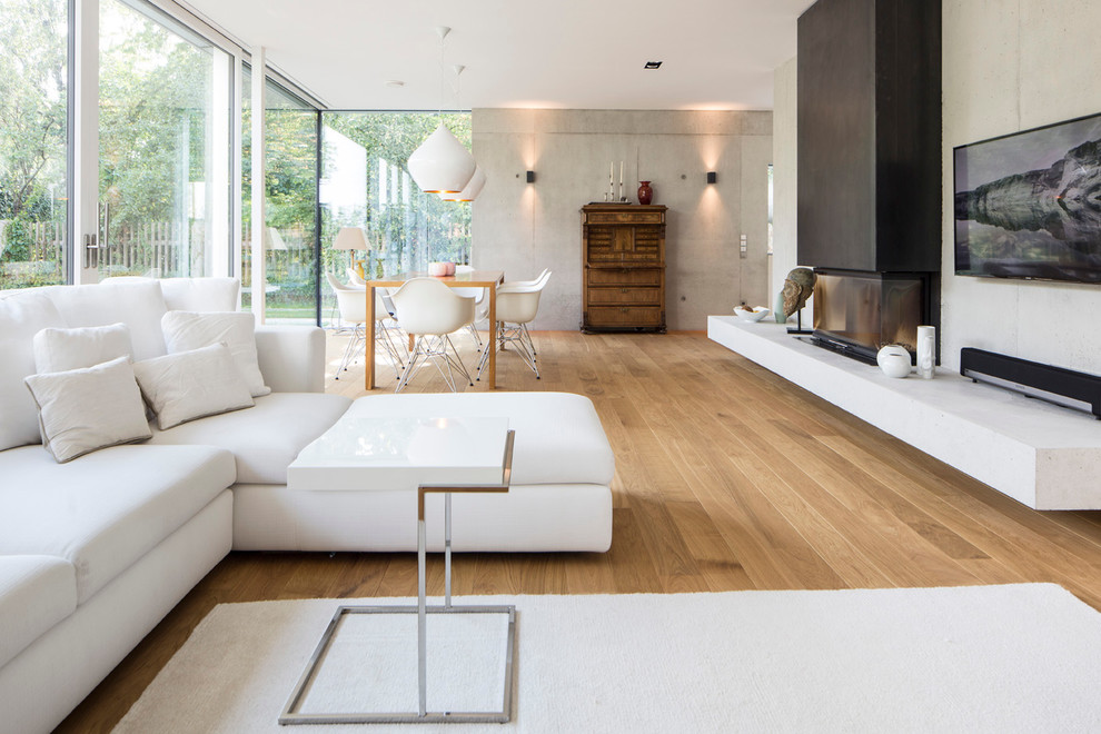 Ispirazione per un grande soggiorno moderno aperto con pareti grigie, pavimento in legno verniciato, camino bifacciale e TV a parete