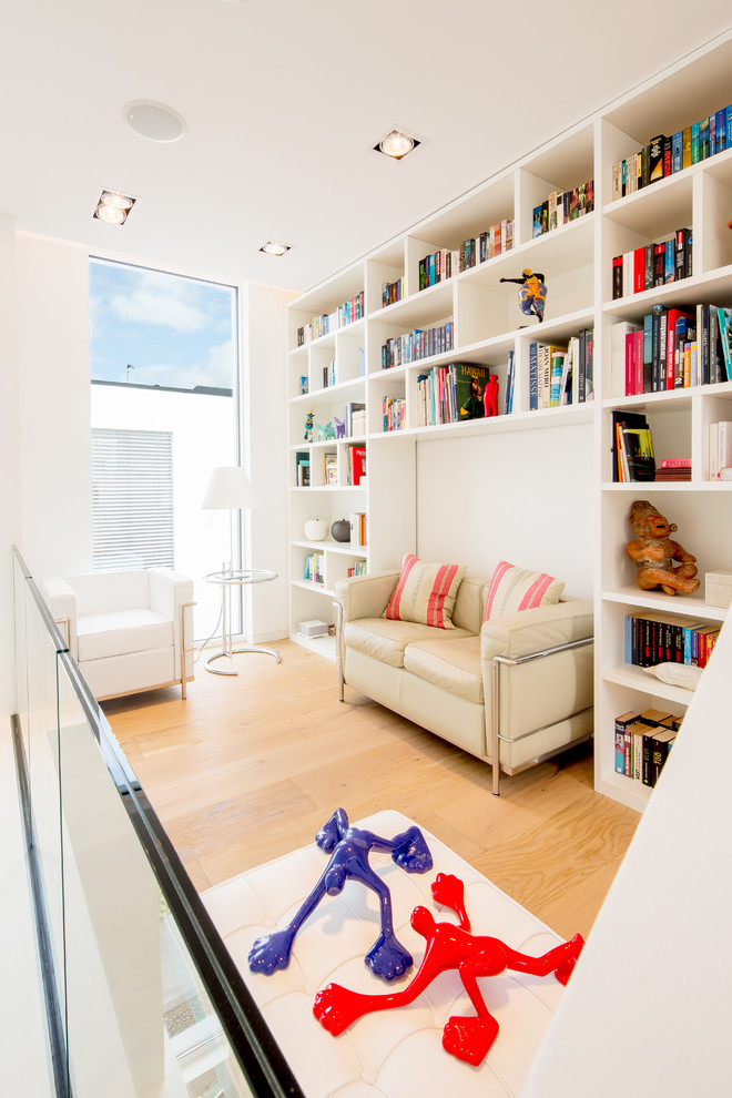 Immagine di un piccolo soggiorno contemporaneo aperto con pareti bianche, pavimento in legno massello medio, pavimento beige, libreria e nessun camino
