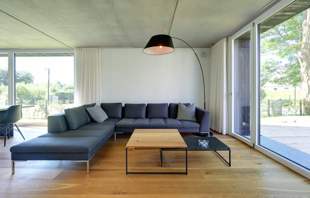 Пример оригинального дизайна: открытая гостиная комната среднего размера в скандинавском стиле с белыми стенами и паркетным полом среднего тона