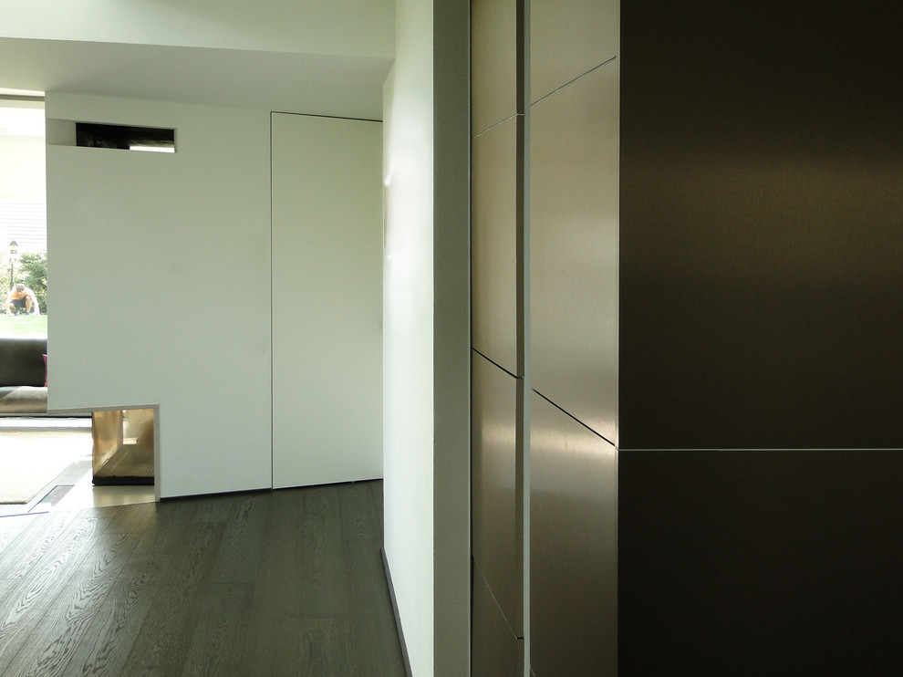 Свежая идея для дизайна: открытая гостиная комната среднего размера в стиле модернизм с темным паркетным полом, угловым камином, фасадом камина из штукатурки и коричневым полом - отличное фото интерьера