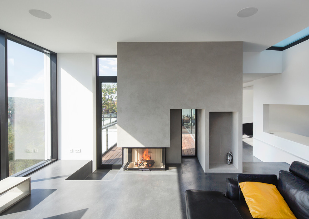 Inspiration for a large contemporary open plan games room in Stuttgart with white walls, a wood burning stove, a plastered fireplace surround, grey floors, a reading nook, concrete flooring and no tv.