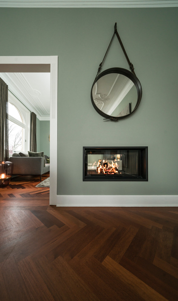 シュトゥットガルトにある高級な広いトラディショナルスタイルのおしゃれなリビング (両方向型暖炉、漆喰の暖炉まわり、緑の壁、無垢フローリング、テレビなし、茶色い床) の写真