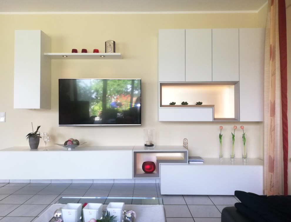На фото: открытая гостиная комната среднего размера в современном стиле с телевизором на стене с