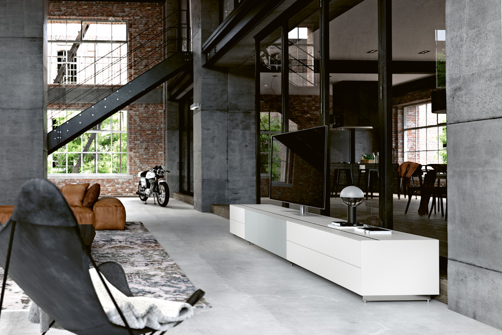 Ejemplo de salón tipo loft urbano grande con paredes grises, suelo de cemento, televisor independiente y suelo gris