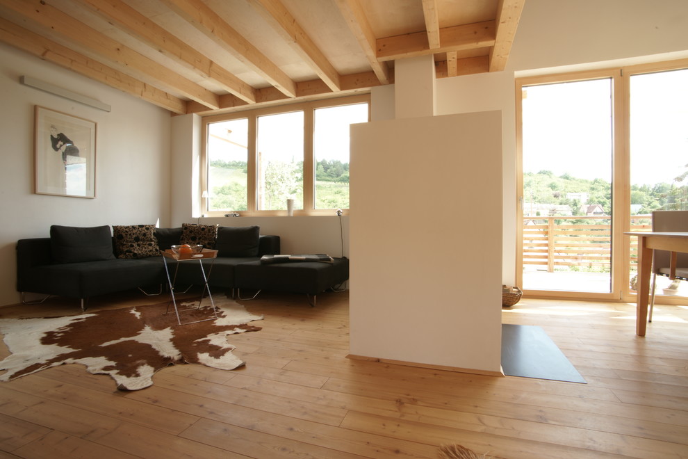 Cette image montre une salle de séjour design de taille moyenne et ouverte avec un mur blanc, parquet clair, une cheminée double-face, un manteau de cheminée en plâtre, un sol beige et poutres apparentes.