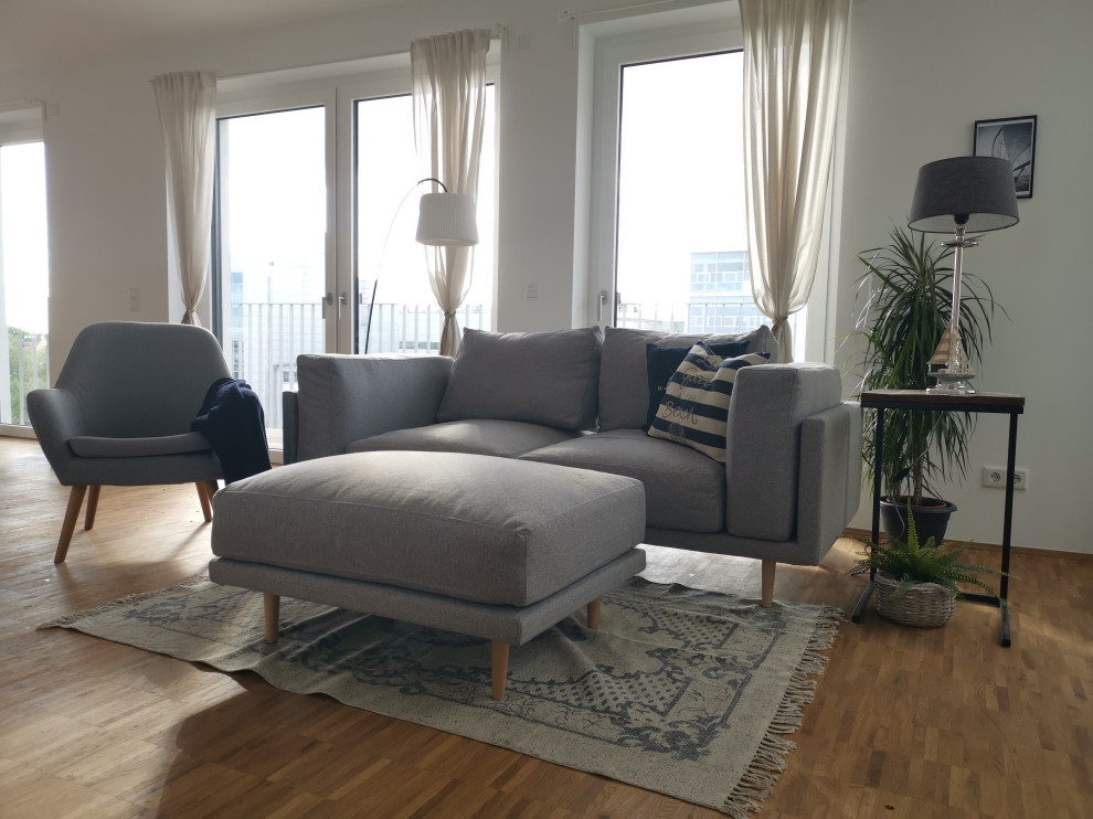 Ejemplo de sala de estar abierta nórdica de tamaño medio con paredes blancas y suelo de madera en tonos medios