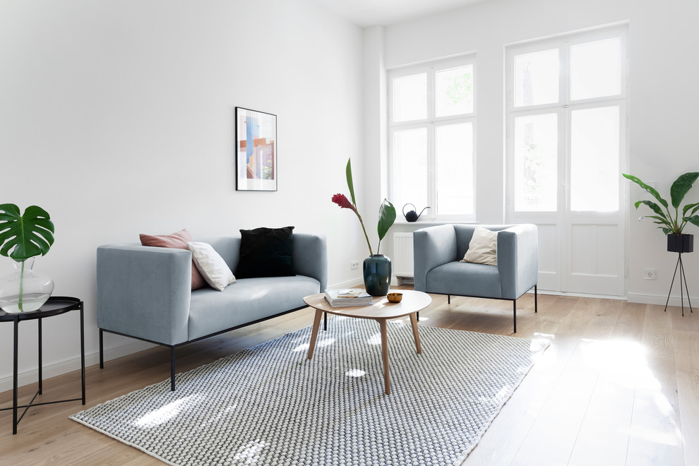 Abgetrenntes Skandinavisches Wohnzimmer mit weißer Wandfarbe, hellem Holzboden und beigem Boden in Berlin