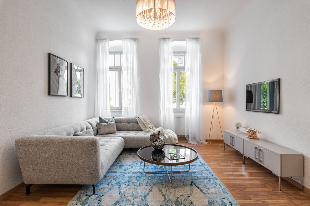 Abgetrenntes Modernes Wohnzimmer mit weißer Wandfarbe, braunem Holzboden, TV-Wand und braunem Boden in Dresden