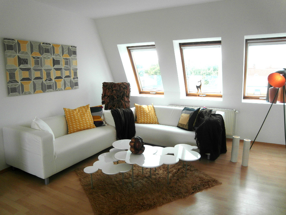 Modelo de salón abierto contemporáneo de tamaño medio con paredes blancas y suelo laminado