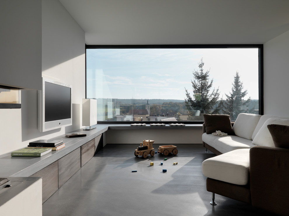 Example of a mid-sized trendy concrete floor family room design in Stuttgart with white walls, a wall-mounted tv and no fireplace