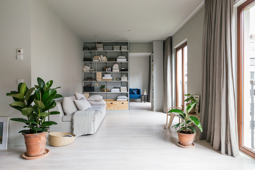 Mid-sized danish open concept light wood floor living room library photo in Berlin with gray walls and no tv