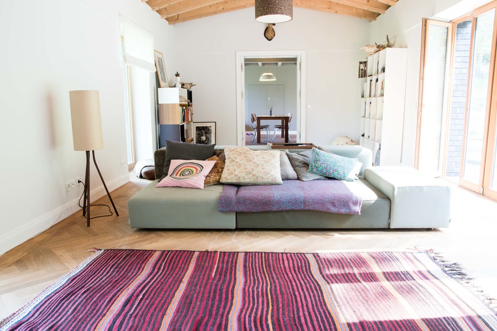 Example of a large trendy enclosed medium tone wood floor living room design in Berlin with white walls and no fireplace