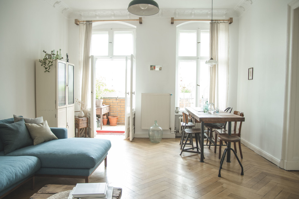 Example of an eclectic medium tone wood floor and brown floor dining room design in Berlin with white walls and no fireplace